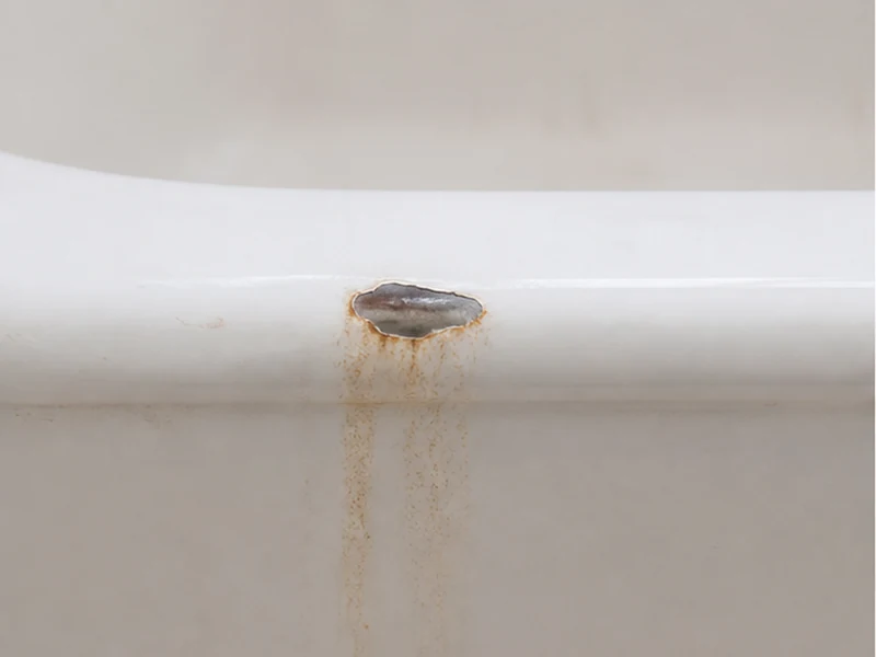 Chipped tub rim with a rust stain spreading from exposed metal in a Sundale home before repair, Fremont